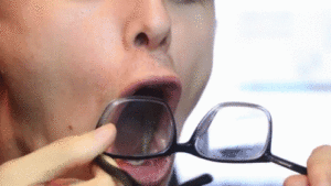 Guy blowing on glasses and cleaning with shirt